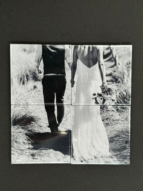 Black and white photo of a two people with their backs facing on four photo magnets tiles 